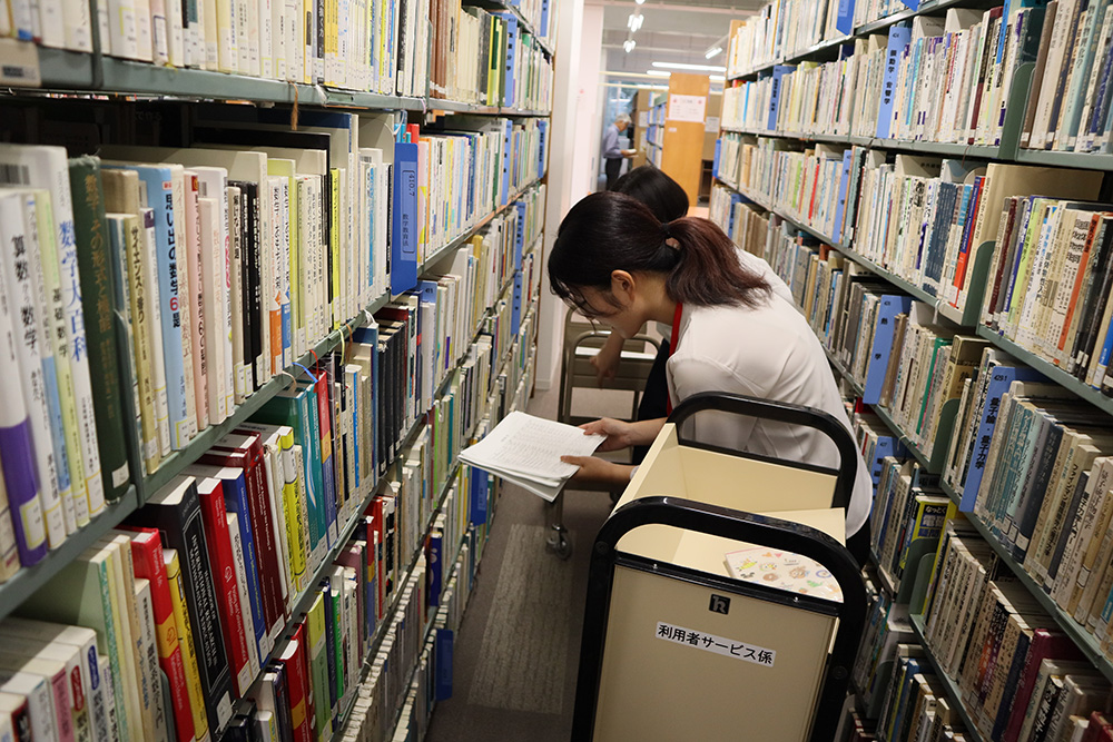 リストをもとに2階の本棚から対象の本を探す様子